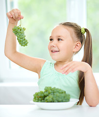 Image showing Cute little girl is looking at green grapes