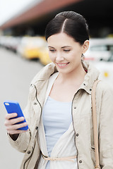 Image showing smiling woman with smartphone over taxi in city