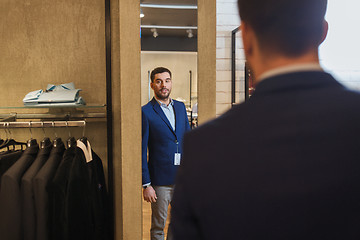 Image showing man trying jacket on at mirror in clothing store