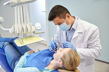 Image showing male dentist in mask checking female patient teeth