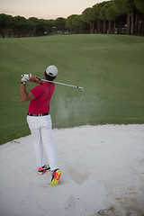 Image showing golfer hitting a sand bunker shot on sunset