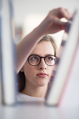 Image showing portrait of famale student selecting book to read in library