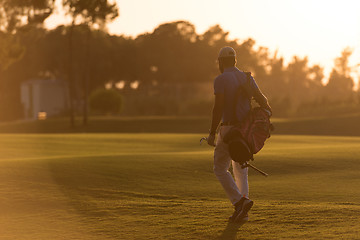 Image showing golfer  walking and carrying golf  bag at beautiful sunset