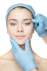 Image showing Plastic surgery concept. Doctor hands in gloves touching woman face