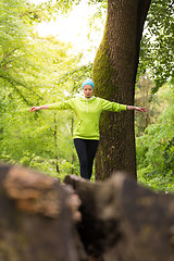 Image showing Woman holding balance on tree trunk in nature.