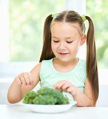 Image showing Cute little girl is eating green grapes