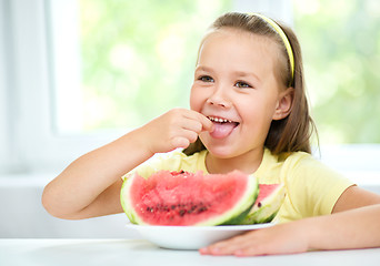 Image showing Cute little girl is eating watermelon