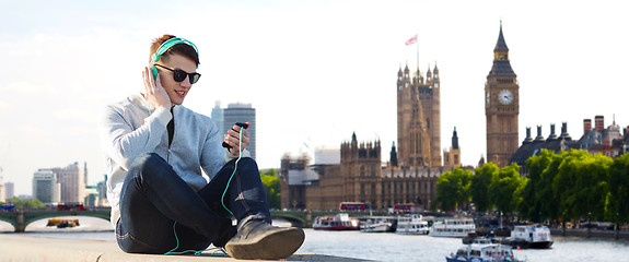 Image showing happy young man in headphones with smartphone