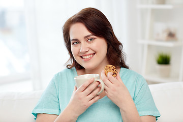 Image showing happy plus size woman with cup and cookie at home