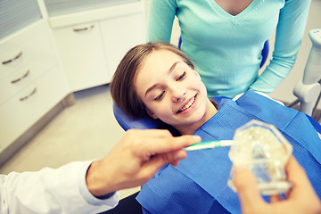 Image showing happy dentist showing toothbrush to patient girl