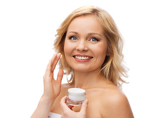 Image showing happy woman applying cream to her face