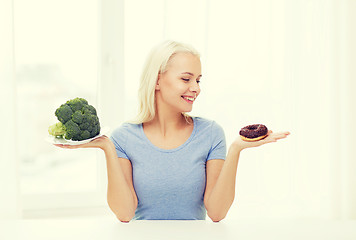 Image showing smiling woman with broccoli and donut at home