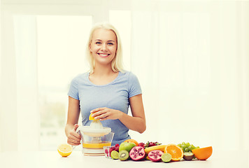 Image showing smiling woman squeezing fruit juice at home