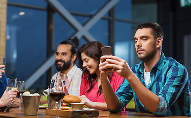 Image showing man with smartphone and friends at restaurant