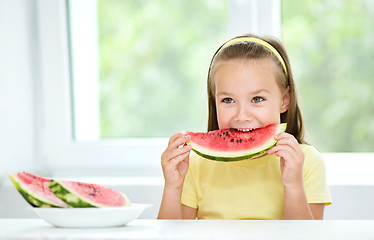 Image showing Cute little girl is eating watermelon