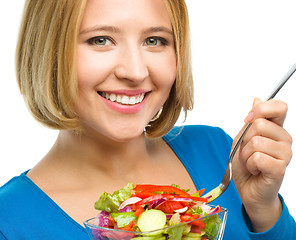 Image showing Young attractive woman is eating salad using fork