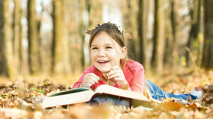 Image showing Little girl is reading a book outdoors