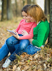 Image showing Mother is reading from tablet with her daughter