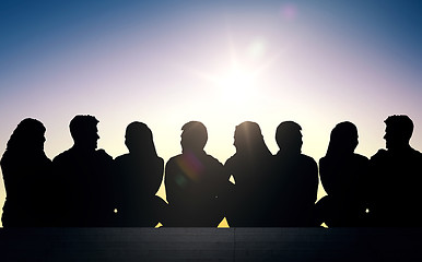 Image showing silhouettes of friends sitting on stairs over sun