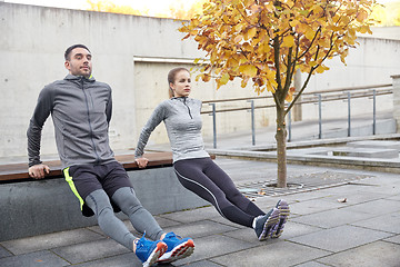 Image showing couple doing triceps dip on city street bench