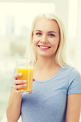 Image showing smiling woman drinking orange juice at home