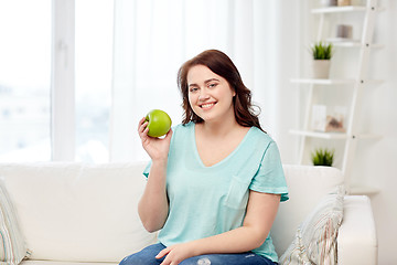 Image showing happy plus size woman eating green apple at home