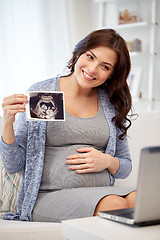 Image showing happy pregnant woman with ultrasound image at home