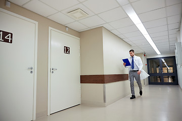 Image showing doctor with clipboard walking along hospital