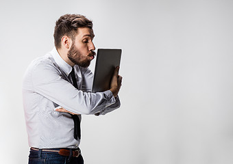 Image showing The young businessman with laptops kissing screen on gray background