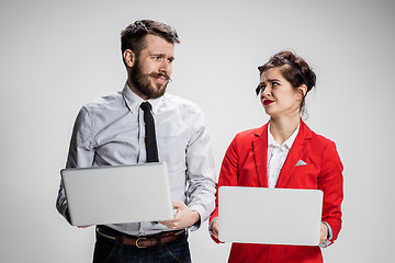Image showing The young businessman and businesswoman with laptops communicating on gray background