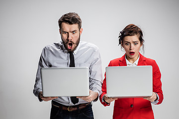 Image showing The young businessman and businesswoman with laptops communicating on gray background