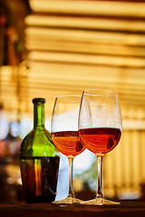 Image showing two glasses filled with red wine and bottle in background