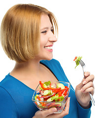 Image showing Young attractive woman is eating salad using fork