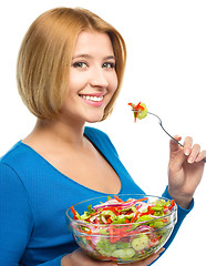 Image showing Young attractive woman is eating salad using fork