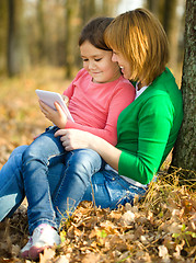 Image showing Mother and her daughter is playing with tablet