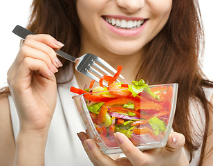 Image showing Young attractive woman is eating salad using fork