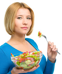 Image showing Young attractive woman is eating salad using fork