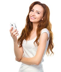 Image showing Young woman is typing sms message on her phone