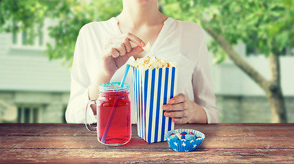 Image showing woman eating popcorn with drink in glass mason jar