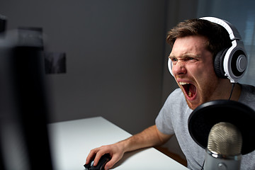 Image showing man in headset playing computer video game at home