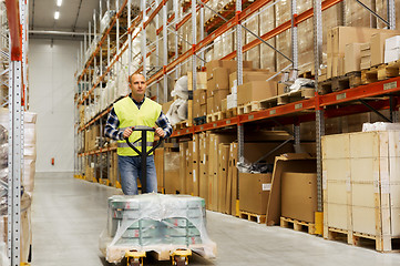 Image showing man carrying loader with goods at warehouse