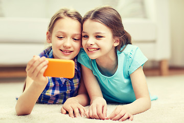 Image showing happy girls with smartphone taking selfie at home