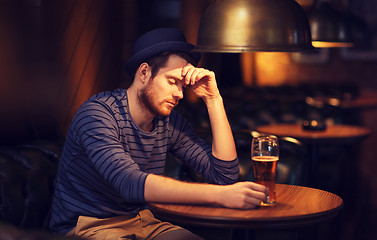 Image showing unhappy lonely man drinking beer at bar or pub