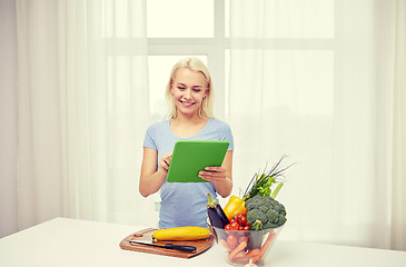 Image showing smiling young woman with tablet pc cooking at home