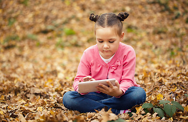 Image showing Little girl is reading from tablet