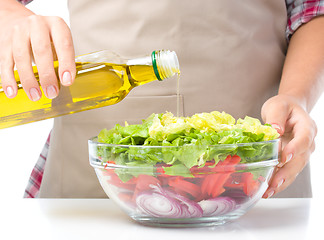 Image showing Cook is pouring olive oil into salad