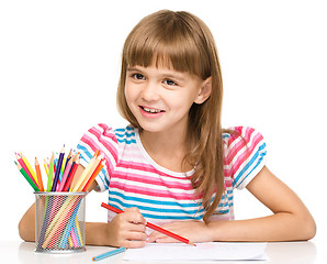 Image showing Little girl is drawing using pencils