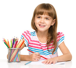 Image showing Little girl is drawing using pencils