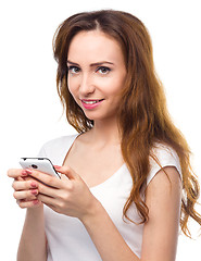 Image showing Young woman is typing sms message on her phone