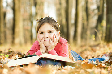 Image showing Little girl is reading a book outdoors